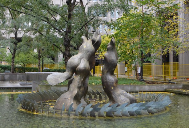 a fountain sculpture called Three Graces, in a circle, surrounded by a shallow pool of water