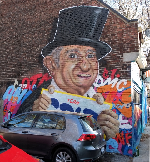 street art portrait of David Mirvish holding iconic Honest Eds signs