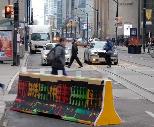 two cars waiting for a red light. a white car and a grey Bentley, pedestrians crossing the intersection in front of them. 