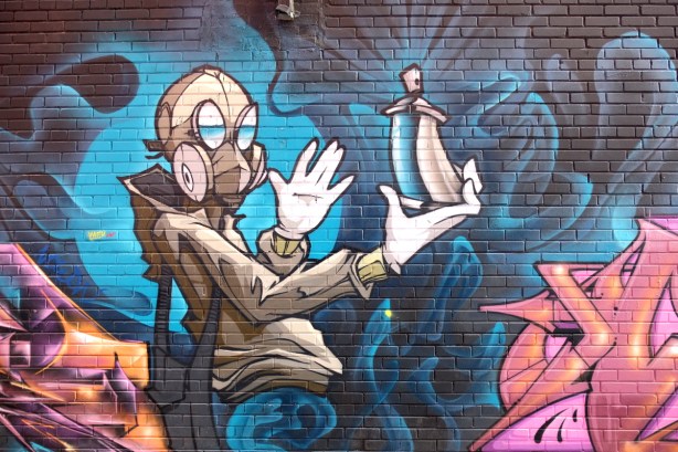 mural in Graffiti Alley - person wearing gas mask and holding a spray paint can in outreached hand 