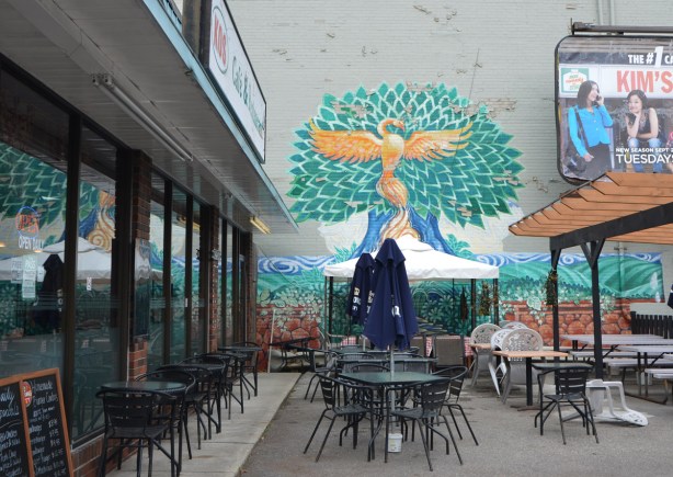 mural on an exterior wall outside Kos restaurant on Bathurst Street, the mural is in the front of the restaurant by the patio, no one sitting outside, blue umbrellas are down. 