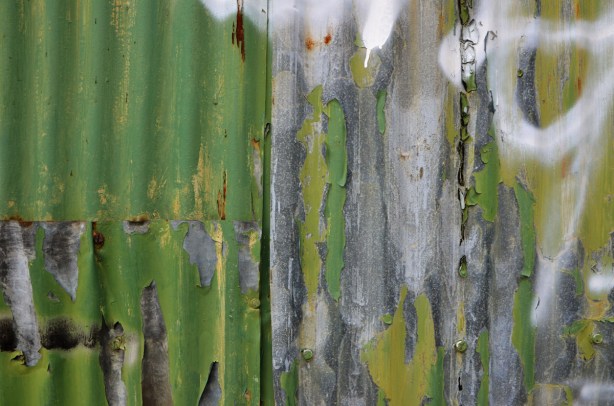 metal corrugated metal wall, close up detail of peeling green paint and rust 