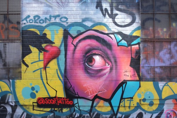 street art painting by soortattoo aka Suren Davtyon, a realistic eye looking to the side, to see a rat holding a red heart