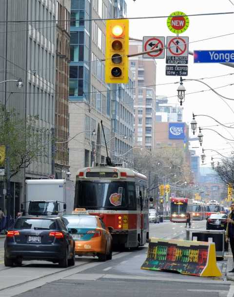 streetcar stopped to let on passengers, cars behind it on the street
