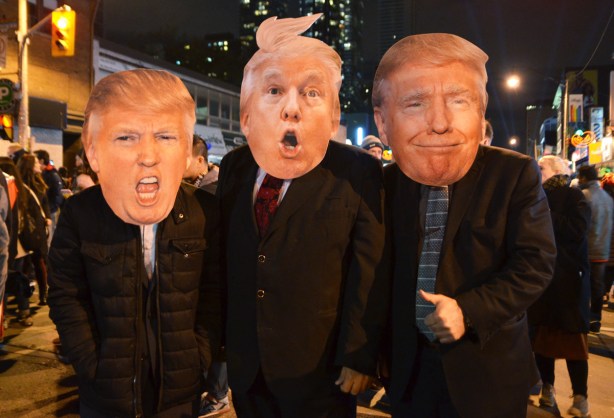 three men in suits and ties with large cardboard Donald Trump faces 