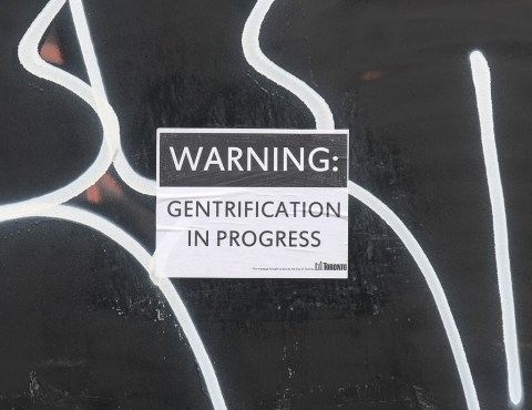 sign on construction oardings that says warning: gentrification in progress