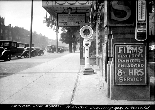 vintage black and white phot of the sidewalk and front of Jewish cinema at the corner of Dundas and Spadina in 1930. old cars parked in front, 