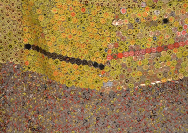artwork hung on a wall, covers the wall, by El Anatsui, a Ghanese artist, made of different colours of liquor bottle caps, metal, close up