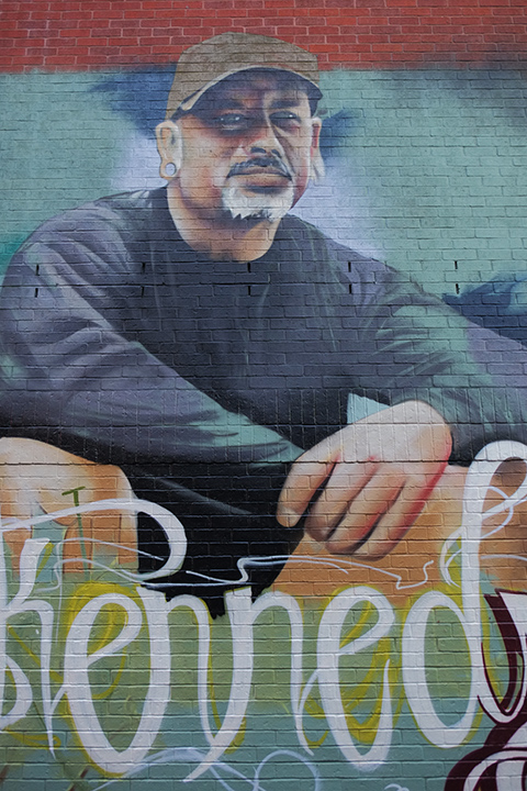middle section of a partially painted mural, in honour of Mike Kennedy, his portrait. 