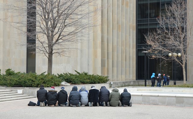 group of men in a line, kneeling, praying, outside,