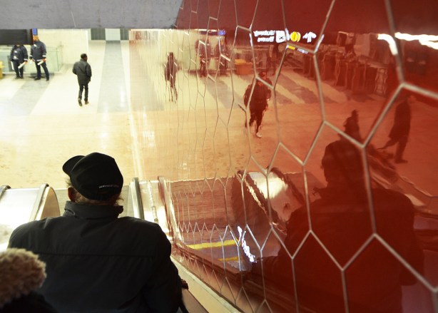 shiny red hexagonal shaped tiles line the wall beside an escalator at the new York University subway station on TTC line 1