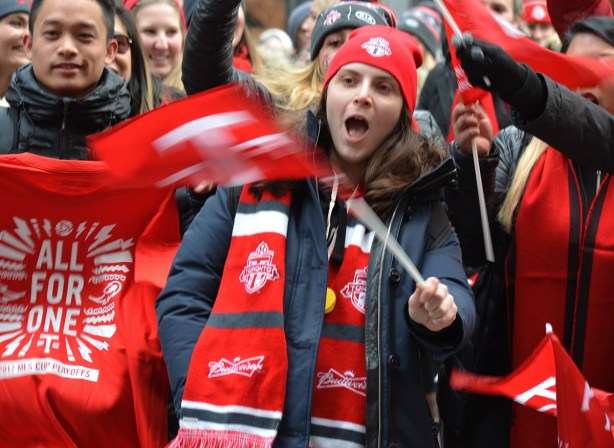 Toronto FC parade, people dressed in red and white, wearing red and white toque and scarf and waving a tfc team flag