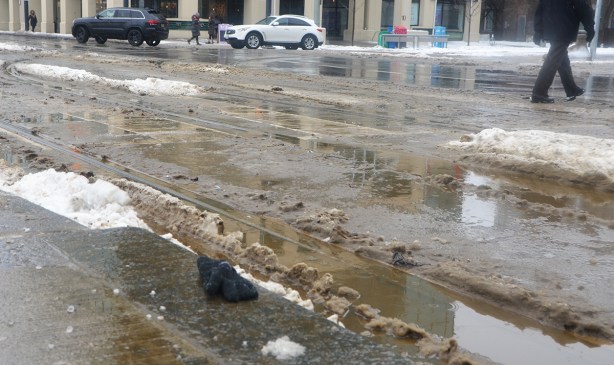 one black wool glove that has been dropped on a slushy wet sidewalk in winter