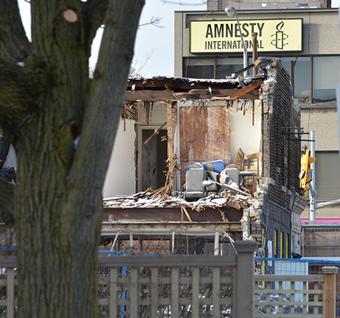 back upper storey of building being torn down, exposing office furniture that was abandoned