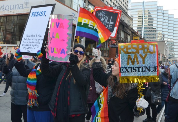 Womens march, protest parade - young women with signs and rainbow peace flags 