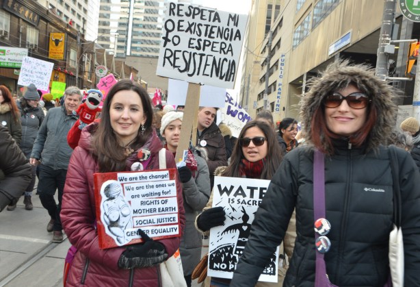 many women marching, many holding placards with protest slogans