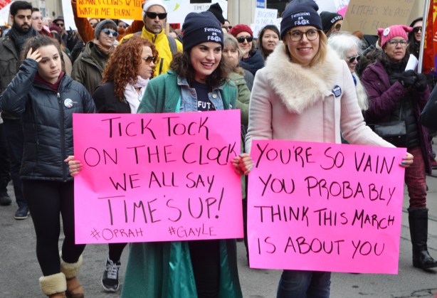 women marching in Womens march, holding pink signs 
