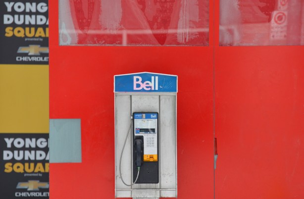 a Bell payphone in front of a red wall. 