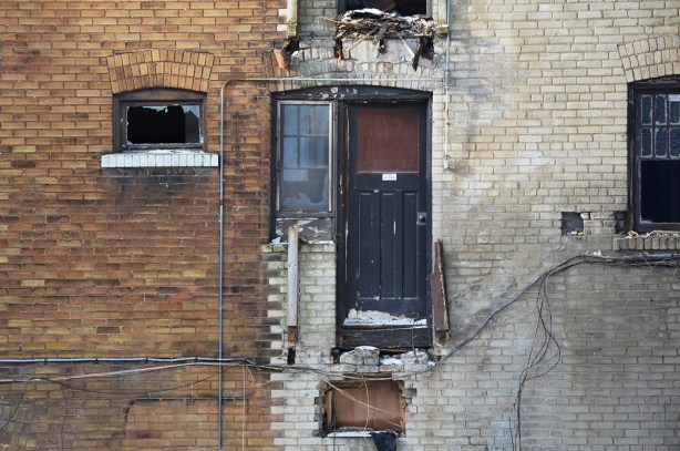 exterior of building being demolished, black door uperlevel with drop below 