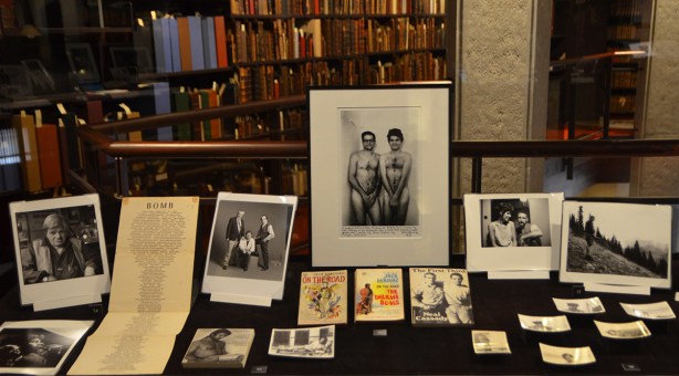 exhibit of photos by Allen Ginsberg displayed in the Thomas Fisher Rare Books Library at U of T, some black and white photos in a case, some books too, shelves of books in the background
