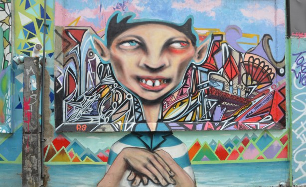 mural of a head and shoulder of a young man, by P.S., in an alley 