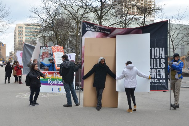 protesters at a right to abortion protest, anti and pro sides, both with a large signs. 
