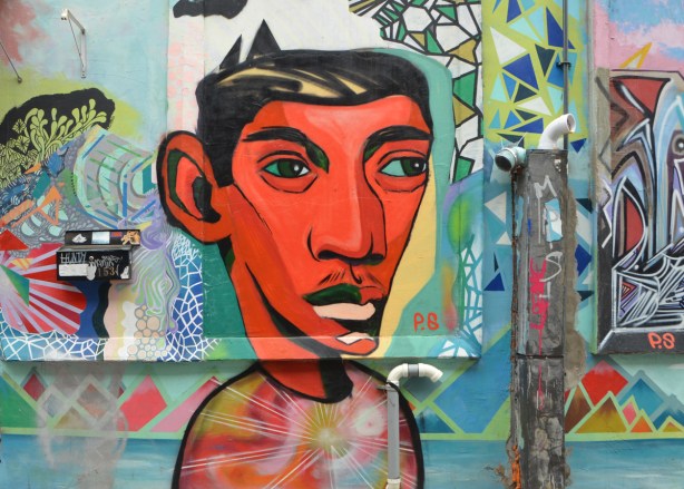 mural of a head and shoulder of a young man, by P.S., in an alley, very red face