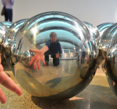 reflections of a person in a few shiny silver balls 