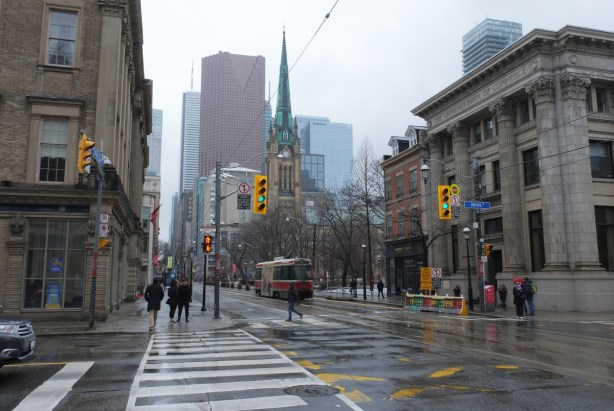 looking west on King street from Jarvis, St. James Cathedral and park on the right, downtown towers and office buildings in the distance, rainy day, TTC streetcar,