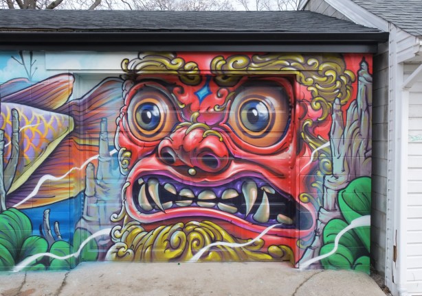part of a mural on a garage door by Bruno Smoky, a large red face of a man. 