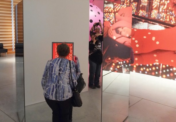 a woman is looking through a small window into a box with mirrors and lights. 