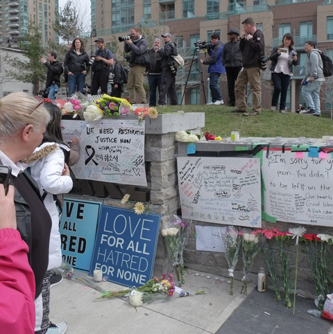 a woman is writing condolences messages on bristol board that has been taped to a stone wall