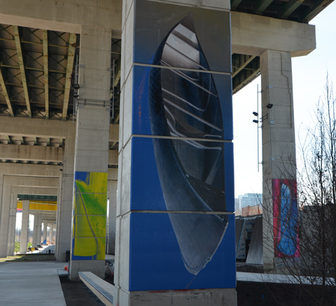 at the Bentway, Dana Claxton's 'Forest of Canoes' art installation of pictures of canoes on the concrete supports of the Gardiner Expressway - grey canoe on black background