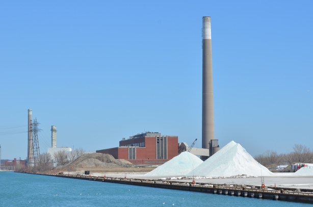 piles of salt on a dock, power generating station in the background.
