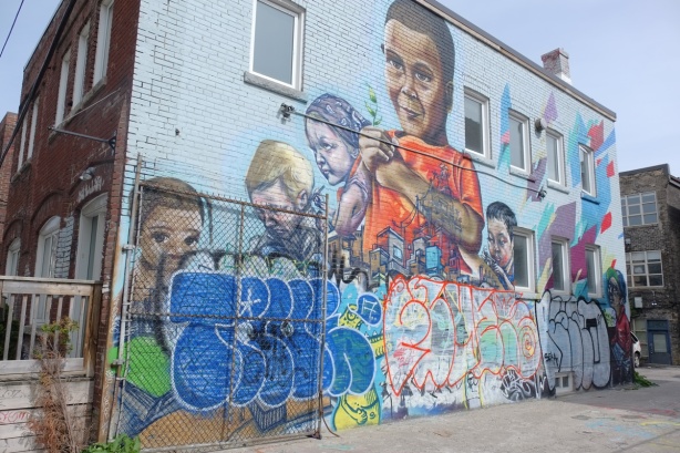 large mural by elicser of kids, bottom part has been covered with three large tags. 