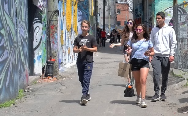 2 young men and 2 young women walking down Graffiti Alley 