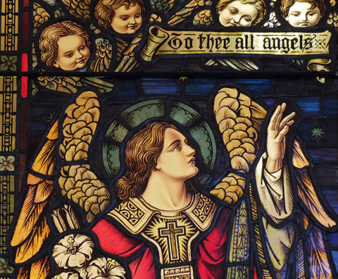 close up of stained glass window, angel, cherub heads, and words that say To thee all angels 