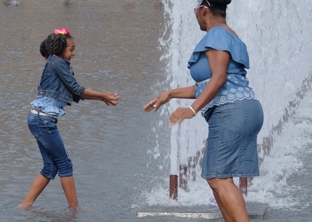 a girl and her mother playing in the fountain at Nathan Phillips Square, in front of city hall, 