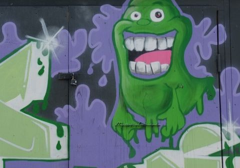 graffiti, purple background, green glob gooey ghost guy with open mouth and big teeth