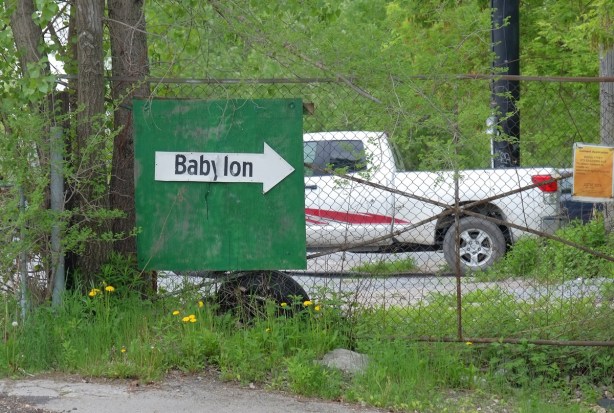 green sign with a large white arrow pointing right. on the arrow is written the word babylon 