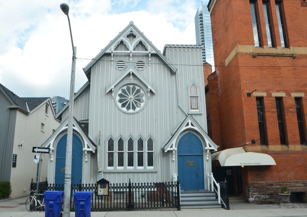 pale blue wood building, originally a church, now the home of the Heliconian Club on Hazelton ave. Bright blue doors, two, rose window, 