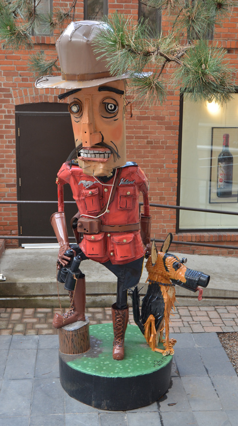 metal junk sculpture by Patrick Amiot of a mountie and his dog, outside, behind a gallery in Yorkville 