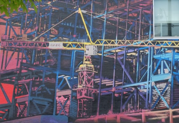 mural of cranes and construction sites on the side of a building, painted by Omen, 