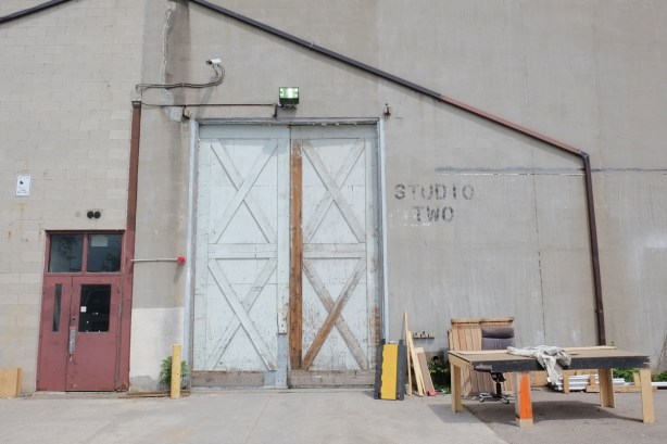 outside a film studio building, large door labelled studio 2, closed doors, some woodworking tools and materials by the door 