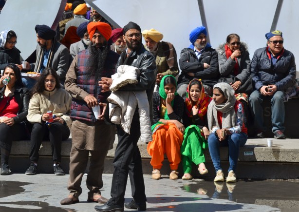 a group of sikhs, men and women, sitting and standing outside