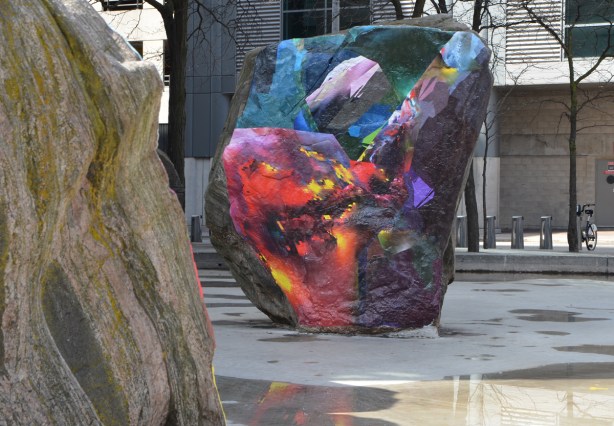 rock covered with a digital image, glued on it, outside, trees around 