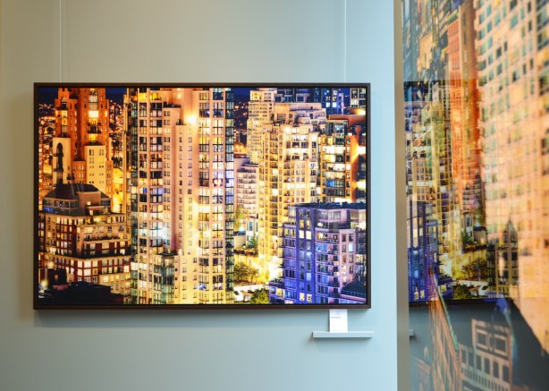 on a gallery wall, Lomas Gallery, a large photo, [a]DCLXI by Amyn Nasser of a wall of glass skyscrapers with lots of windows, on the wall beside is another photo in which Nasser's photo is reflected. 