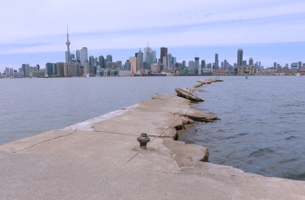 broken concrete pier into Inner Harbour of Lake Ontario, with Toronto skyline and CN Tower in the distance 