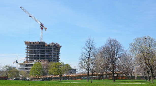 construction of an elevated ramp beside a park from a distance, with condo building going on behind it 
