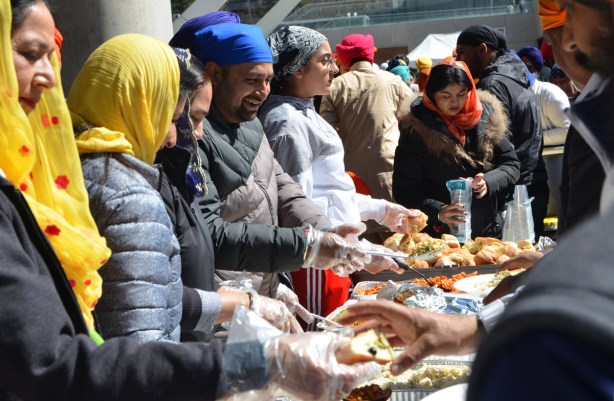 male and female volunteers serve food to people at khalsa celebrations. 